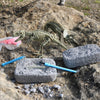 Toy dinosaur skeleton on a rocky surface with tools