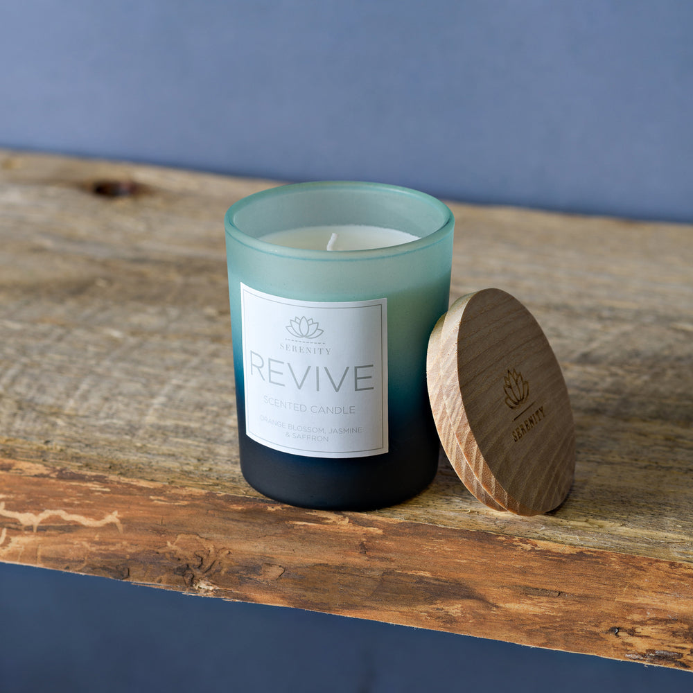 Candle labeled 'REVIVE' with a wooden lid on a wooden surface