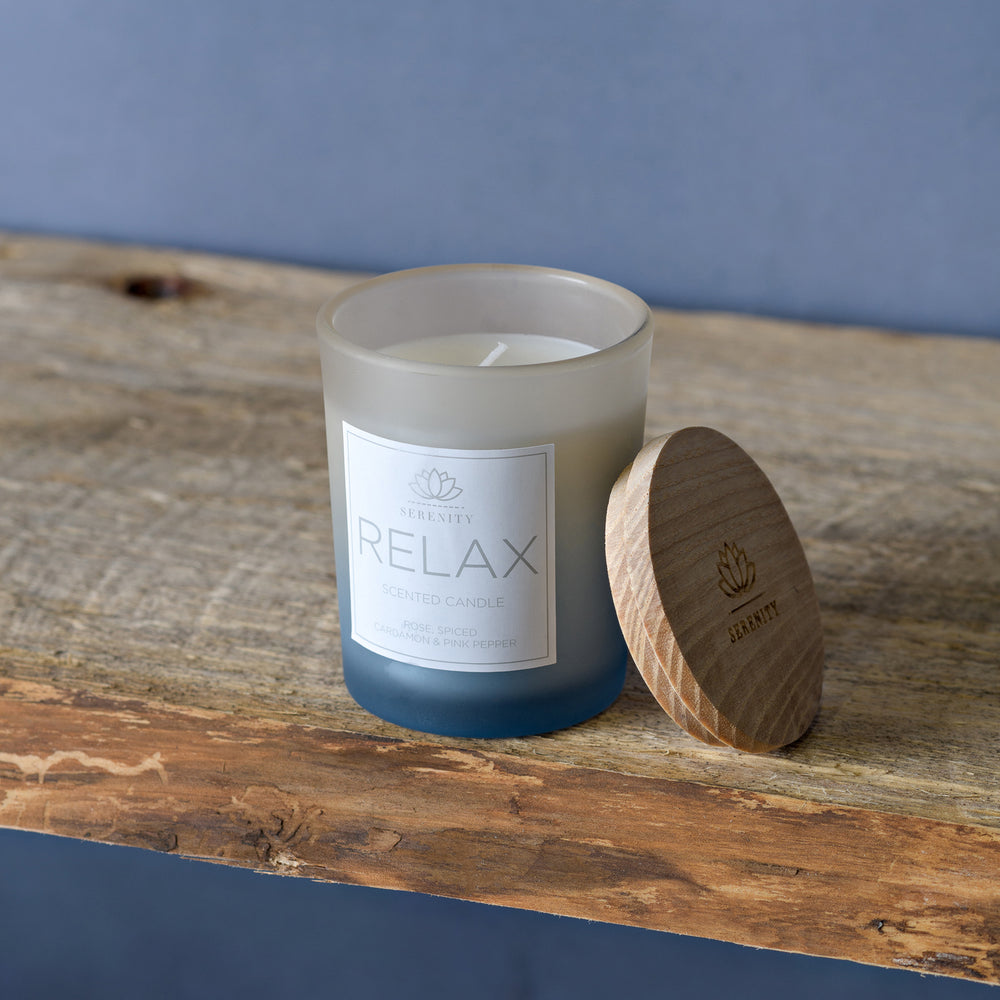 Candle labeled 'Relax' with wooden lid on a wooden surface