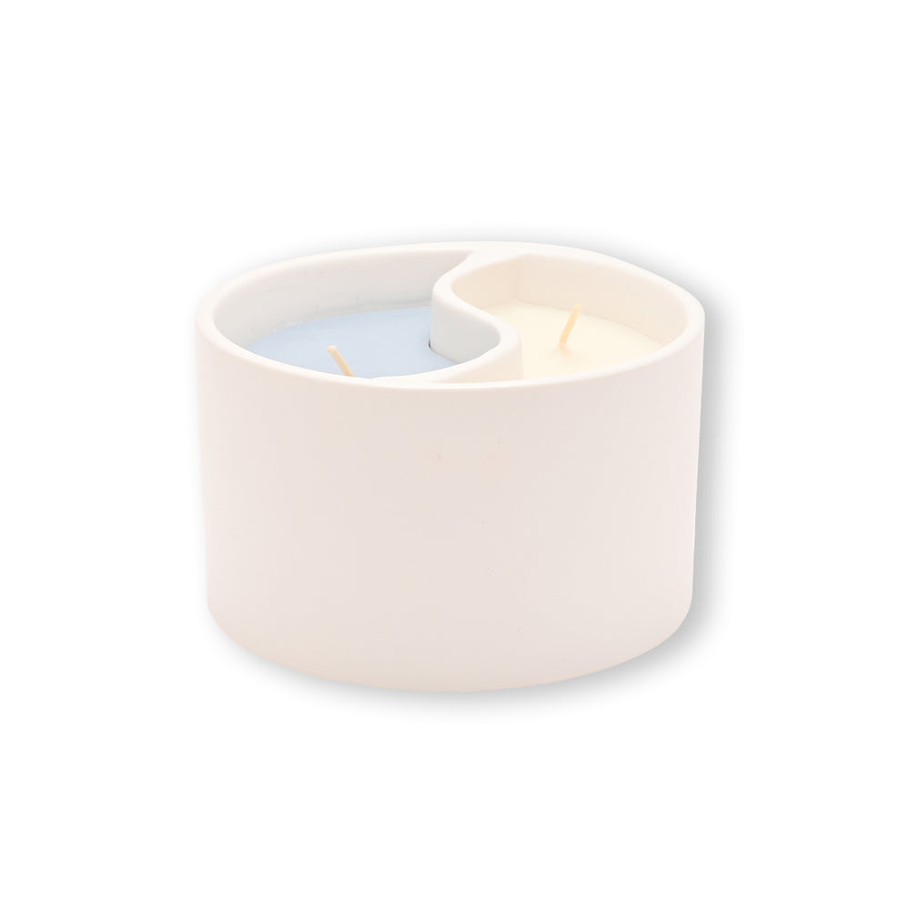 White ceramic candle holder with a blue  and white candles in a yin yan design on a white background