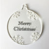 Round Christmas ornament with 'Merry Christmas' text and braille with snowflake designs on a white background.