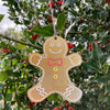 Gingerbread man ornament hanging on a holly branch with red berries