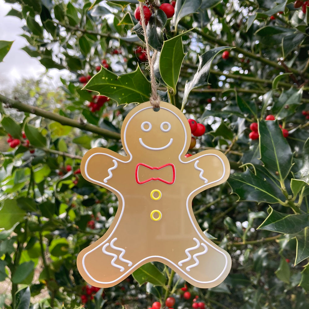 Gingerbread man ornament hanging on a holly branch with red berries