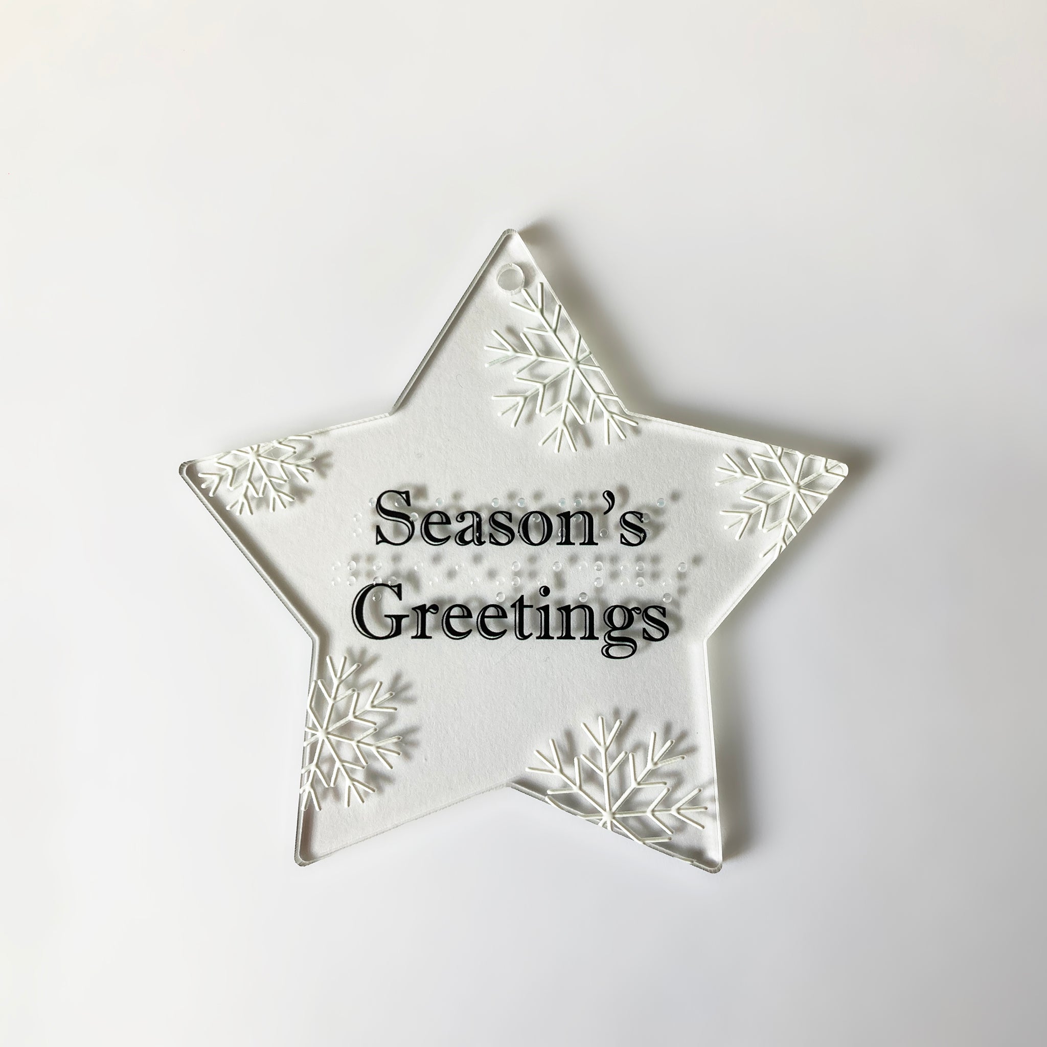 Star-shaped decorative ornament with 'Season's Greetings' in text and braille  on a white background
