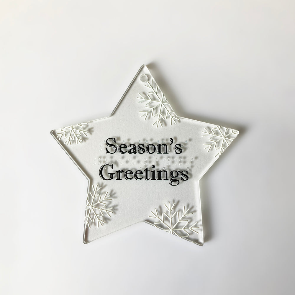 Star-shaped decorative ornament with 'Season's Greetings' in text and braille  on a white background