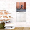 Calendar on a brick wall with books and sunglasses below
