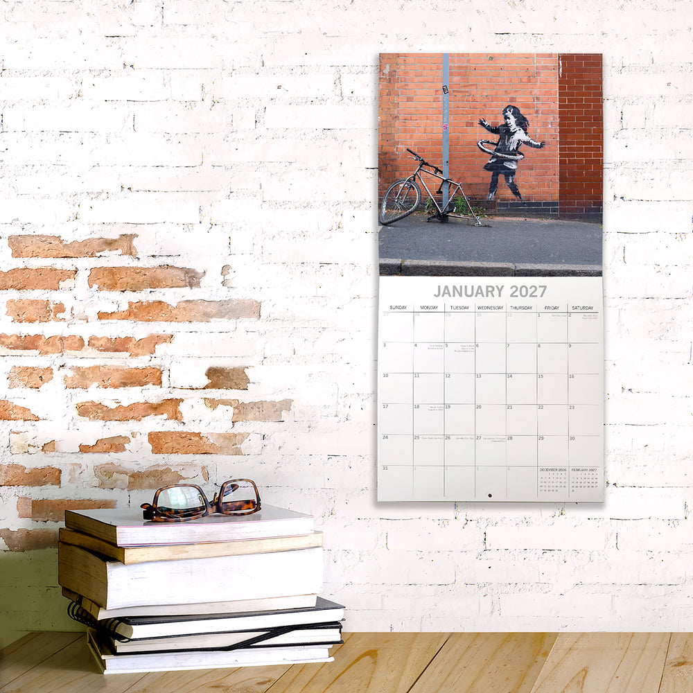 Calendar on a brick wall with books and sunglasses below