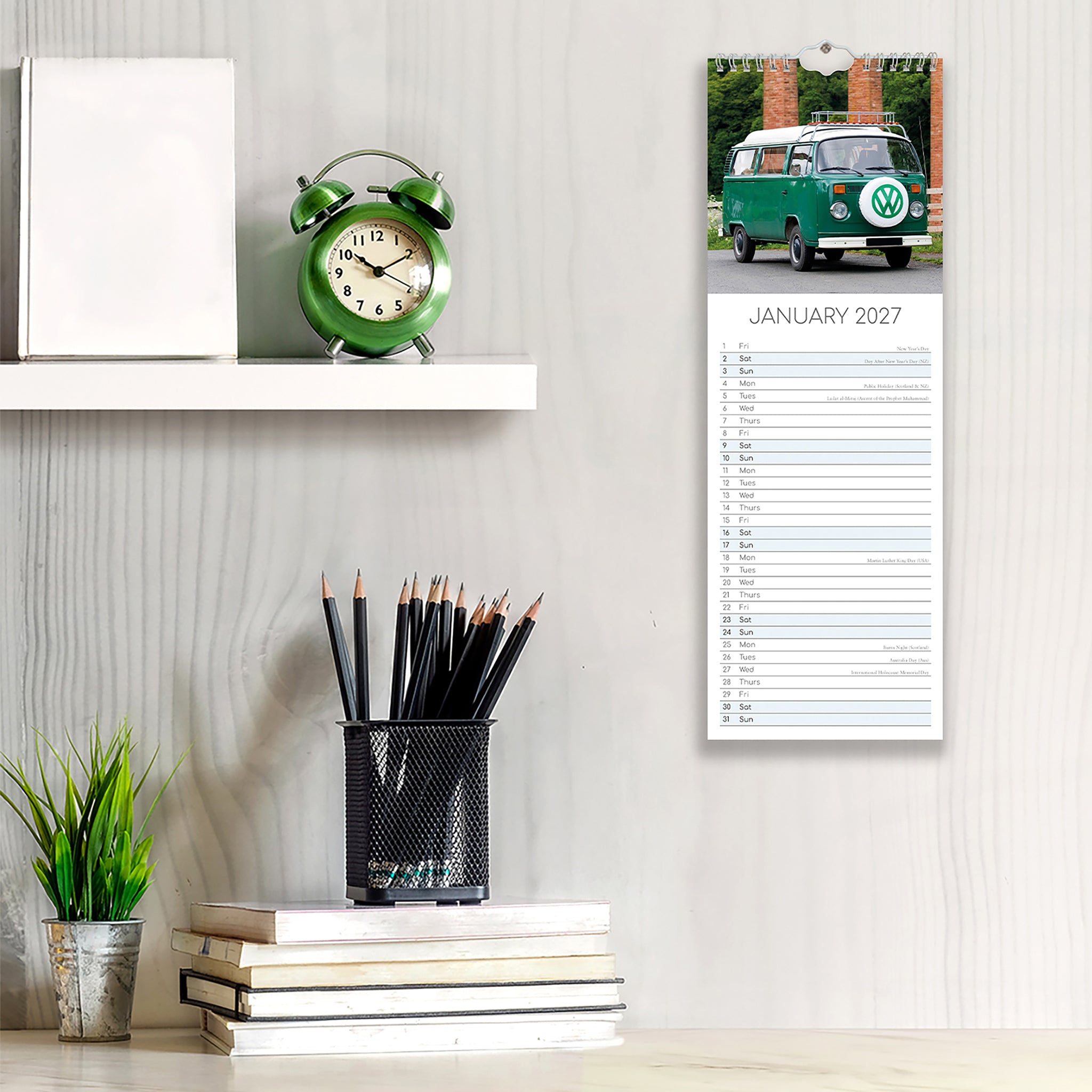 Calendar with a green van design on a wall next to stationery items.