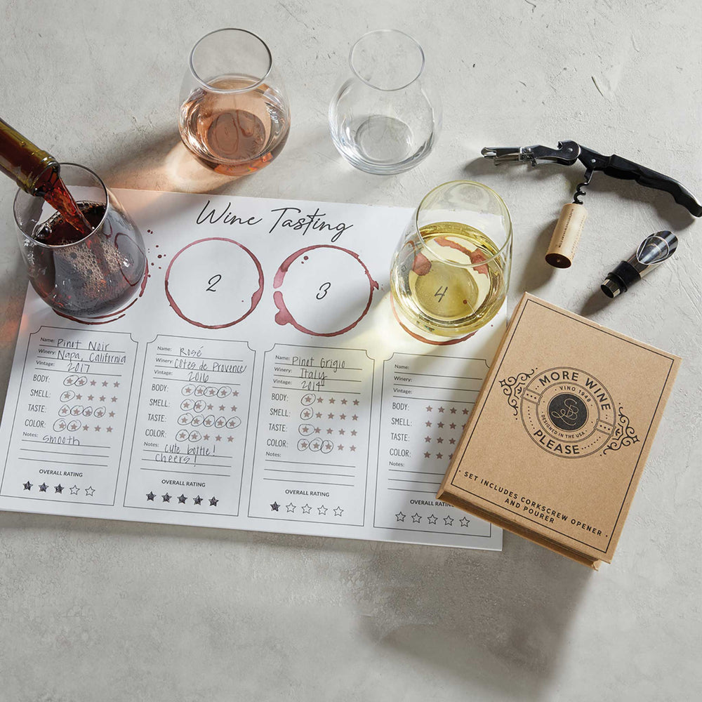 Wine tasting setup with glasses, a box, and a tasting sheet on a light surface.