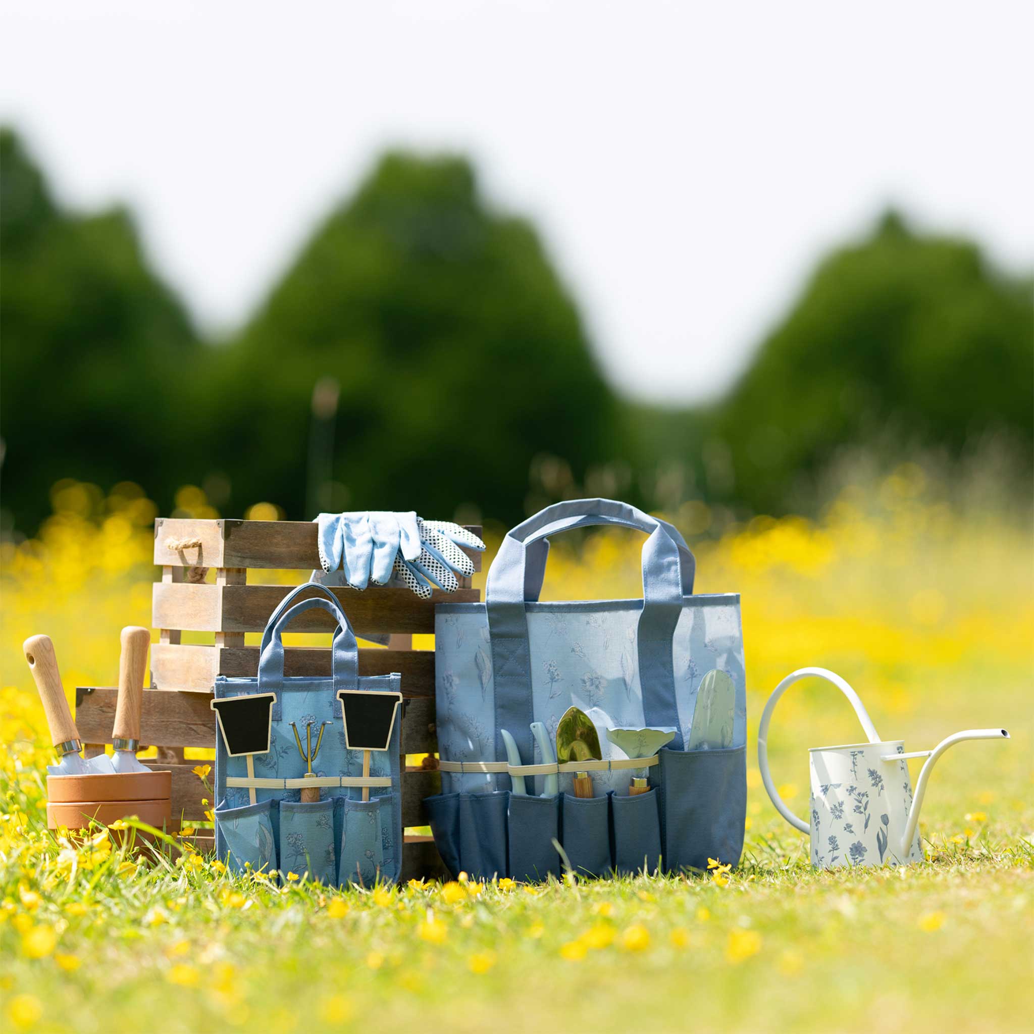 Gardening tools and accessories on a grassy field with blurred trees in the background