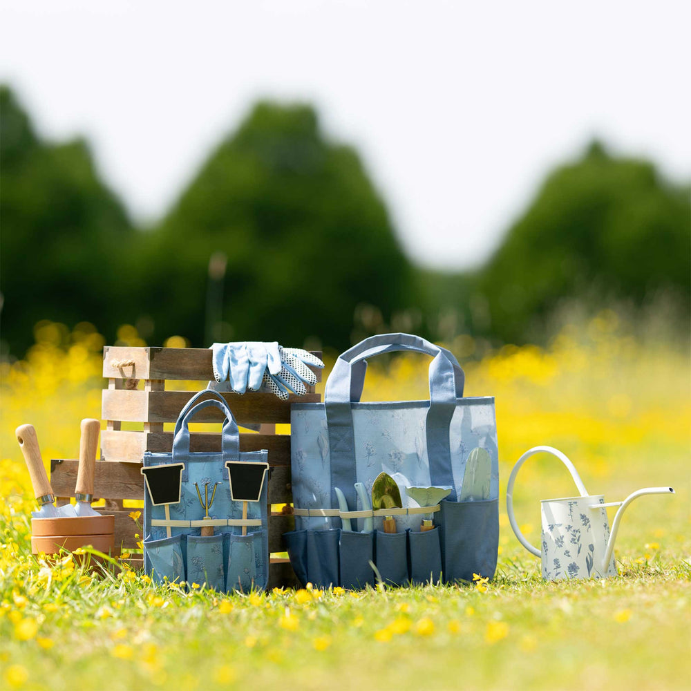 Gardening tools and accessories on a grassy field with blurred trees in the background
