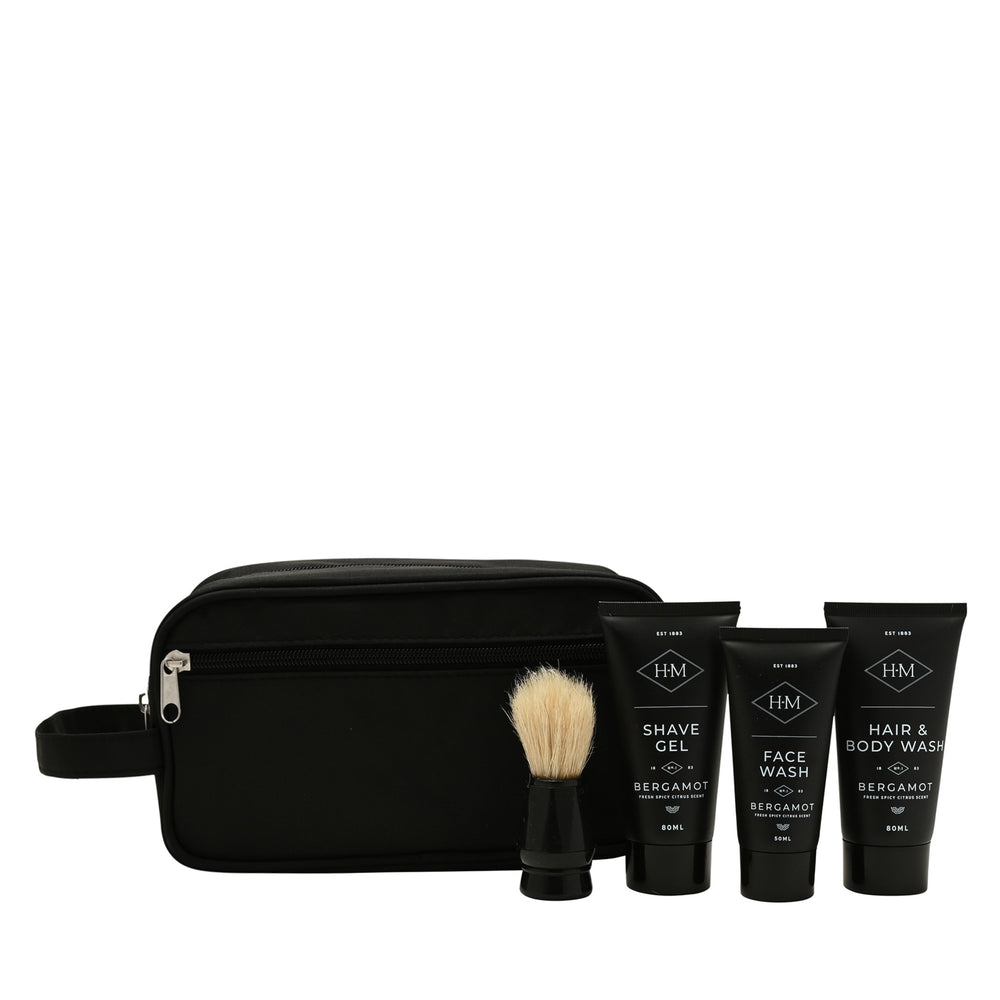 Black toiletry bag with shaving brush and three bottles of grooming products on a white background
