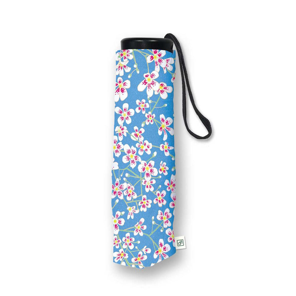 A rolled-up compact umbrella with a blue floral print, featuring white blossoms with pink and yellow centers, a black top cap, and a black wrist strap, shown on a white background.