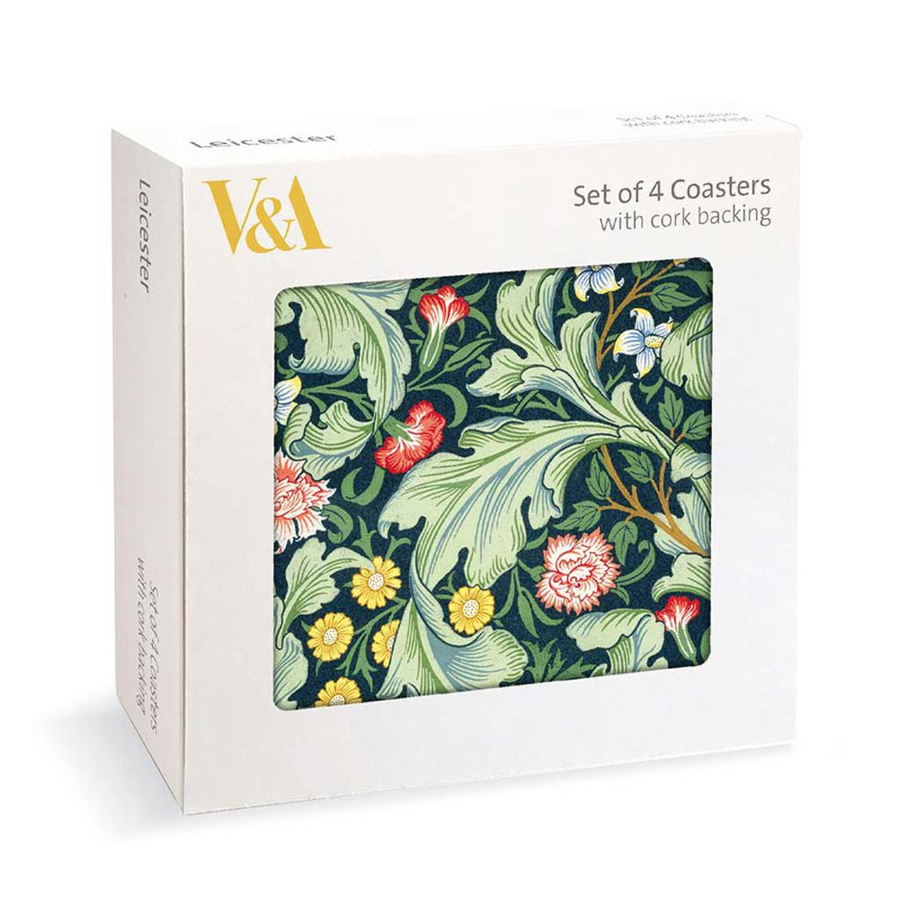 A white V&A product box showing a floral coaster set with cork backing. The front of the box features a large square window displaying a dark green coaster with a classic botanical pattern of large green leaves, yellow and red flowers, and small blue blossoms.