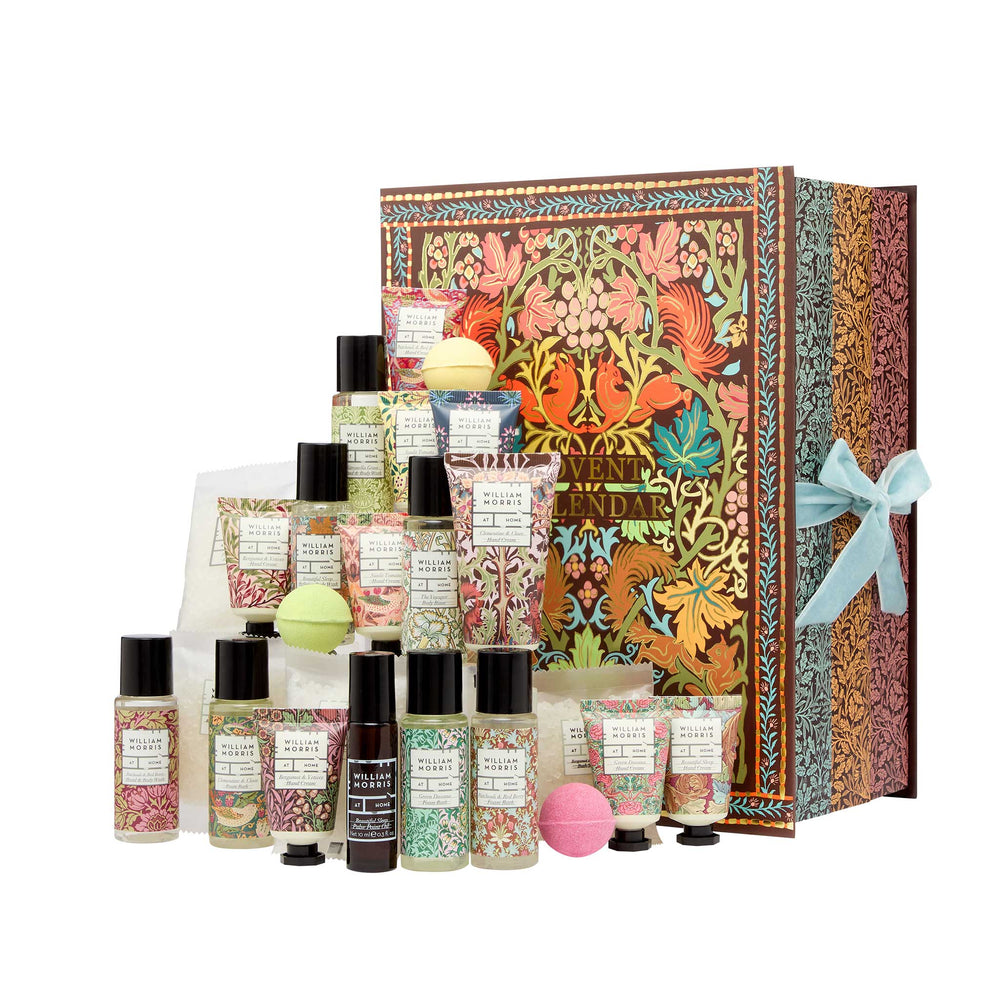 A luxury bath and body gift set featuring a large decorative box with an ornate floral pattern and a light blue ribbon, surrounded by assorted toiletries including bottles, tubes, and round bath bombs on a white background.