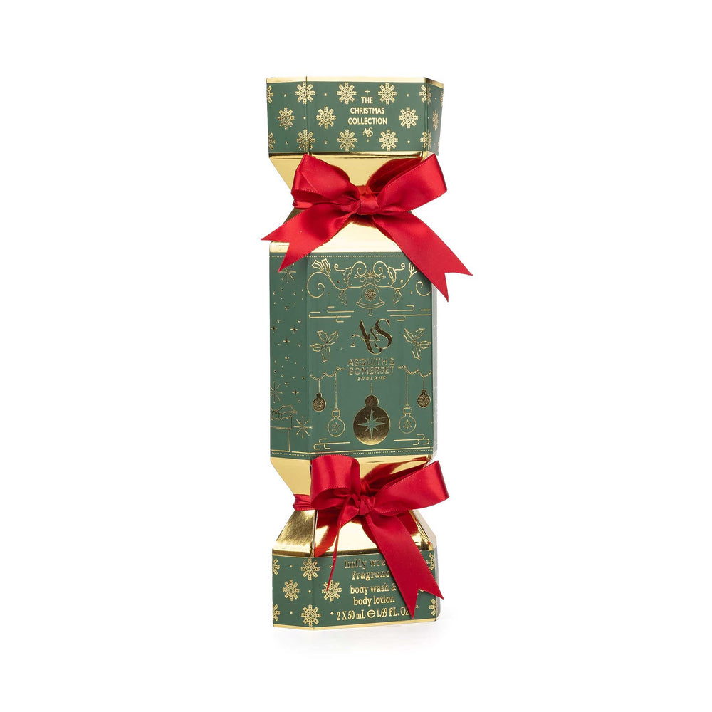 A Christmas-themed cylindrical box with a green and gold patterned design, tied with two red satin bows, on a plain white background.