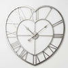 Heart-shaped metal wall clock with an open-frame design, Roman numerals, and decorative hands on a plain white background.