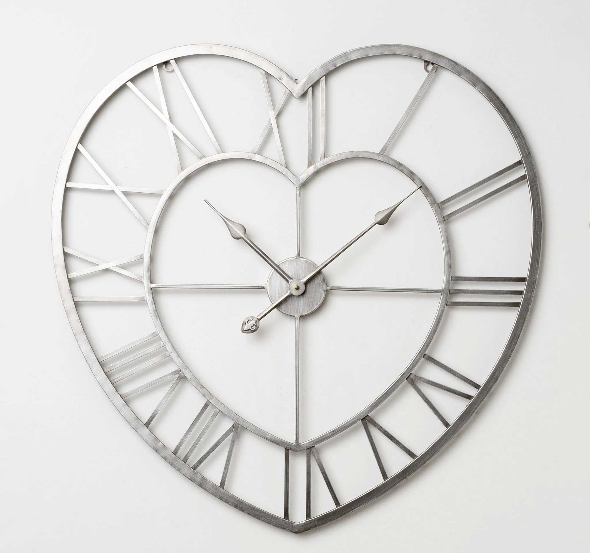 Heart-shaped metal wall clock with an open-frame design, Roman numerals, and decorative hands on a plain white background.