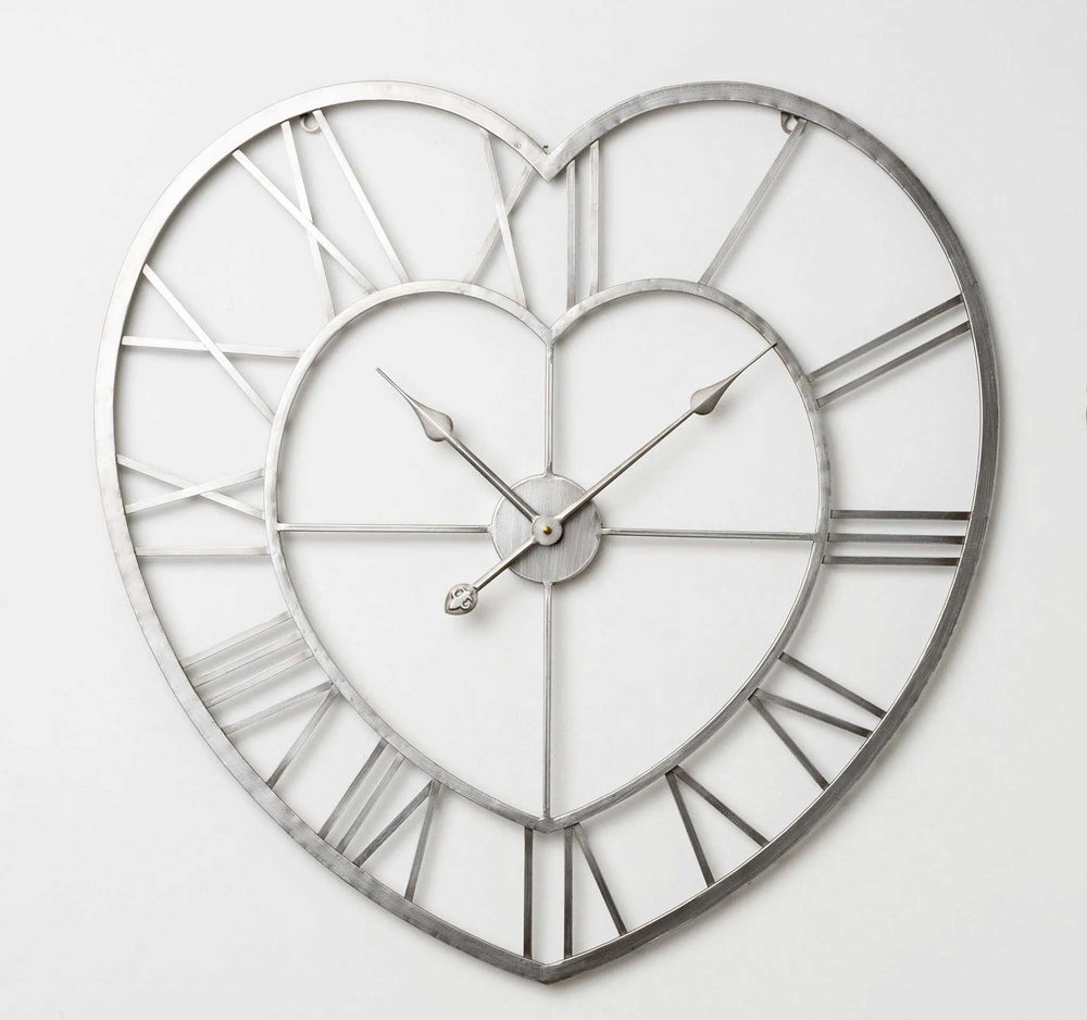 Heart-shaped metal wall clock with an open-frame design, Roman numerals, and decorative hands on a plain white background.