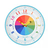 A colorful children's wall clock with a white face, light blue border, and rainbow-colored clock face segments. The clock includes hour, minute, and quarter-hour markings with yellow clock hands in the shape of crayons.