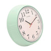 A round wall clock with a sage green frame, a white face, black numerals, black hands, and a red second hand.
