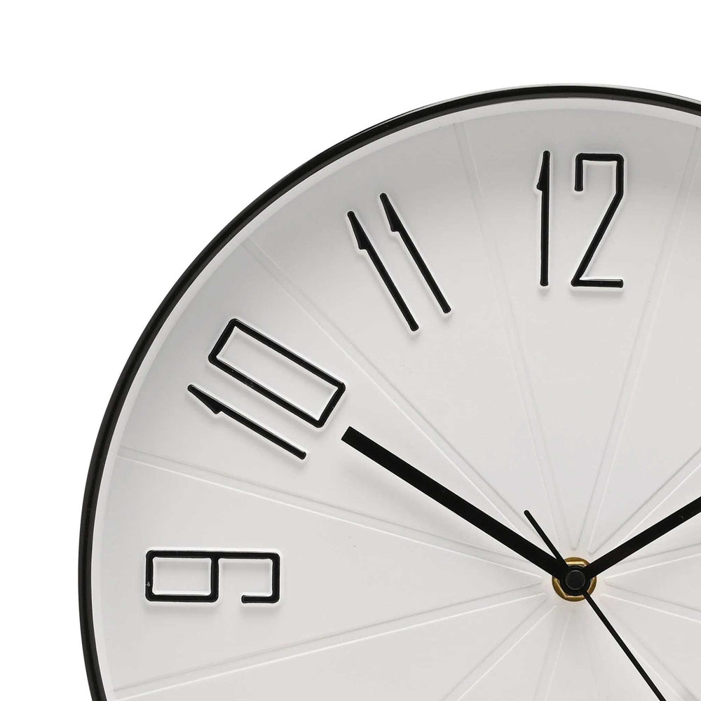 Close-up of a minimalist wall clock face showing the numbers 9, 10, 11, and 12 in a modern cutout style. The clock has a white face with black hands and a black outer rim, with a small gold accent at the center.