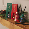 Decorative diffusers with 'Peace' and 'Joy' packaging on a wooden surface with greenery.