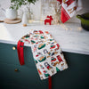 Decorative kitchen apron with Christmas-themed design hanging on a cabinet handle.
