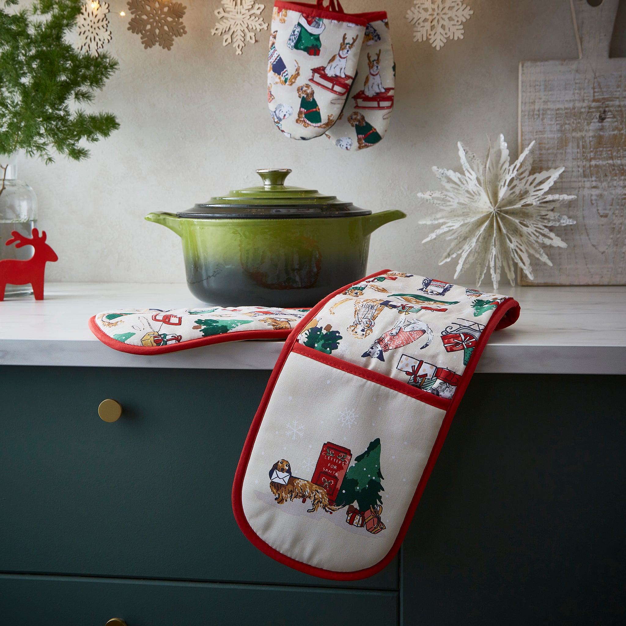 Decorative oven glove with Christmas designs hanging on a kitchen counter.